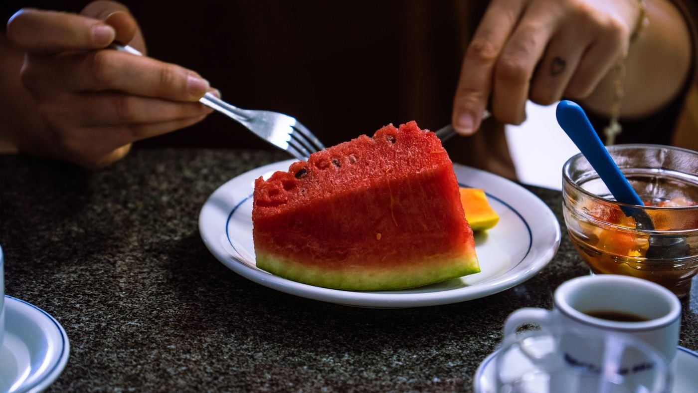 Hóspede se servindo de frutas e café na mesa do café da manhã