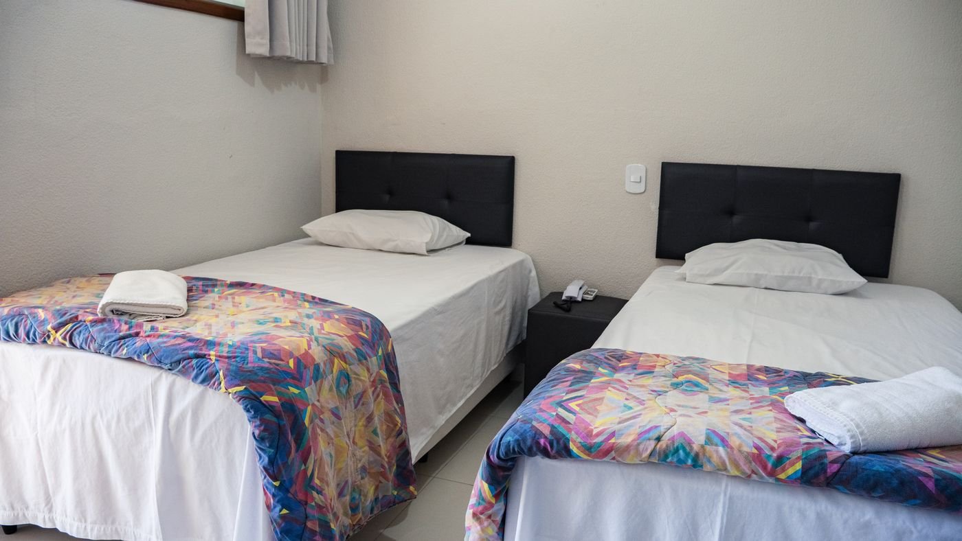Camas arrumadas com roupa de cama colorida no apartamento duplo